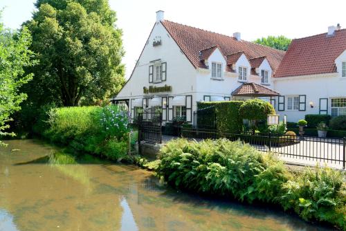 une maison avec une rivière devant elle dans l'établissement De Watermolen, à Kasterlee