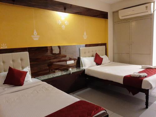 una camera d'albergo con due letti con cuscini rossi di Ravi Krishna Inn a Pondicherry