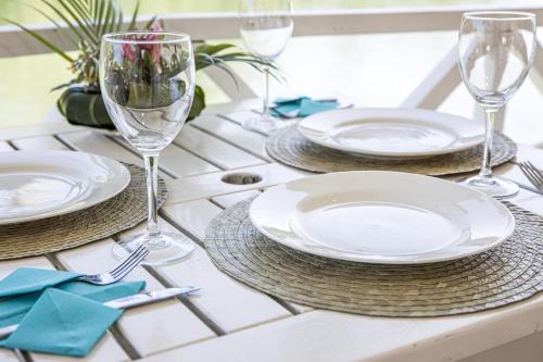 a table with plates and wine glasses on it at Tropicana Lagoon Apartments in Port Vila