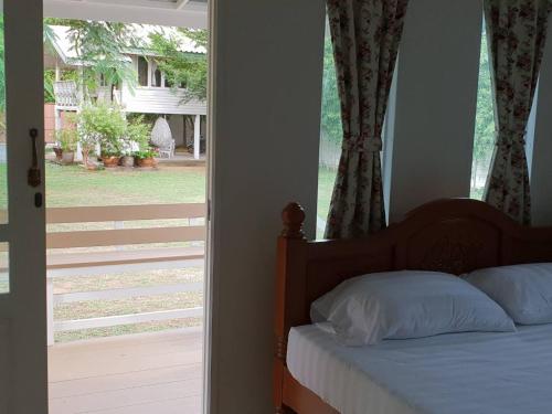 een slaapkamer met een bed naast een glazen schuifdeur bij Baan Suan Yensabai @Ayutthaya in Phra Nakhon Si Ayutthaya