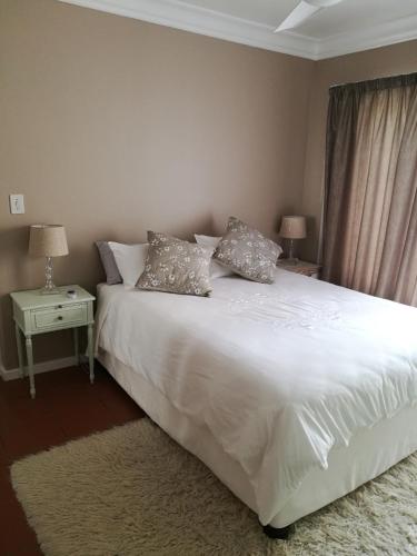 a bedroom with a white bed with two pillows on it at Lucias Cottage in Cape Town