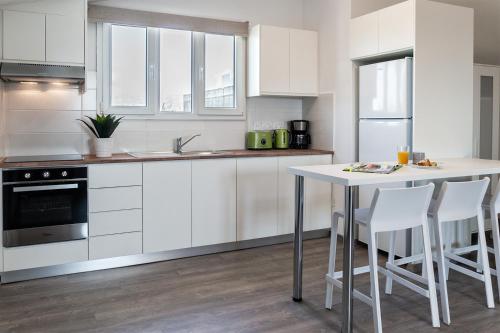 a kitchen with white cabinets and a table and chairs at Silver Apartment - Loft in Limassol