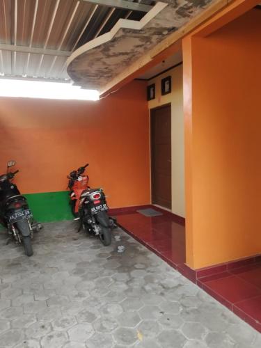 two motorcycles parked in a room with orange walls at Primadona Homestay in Sleman