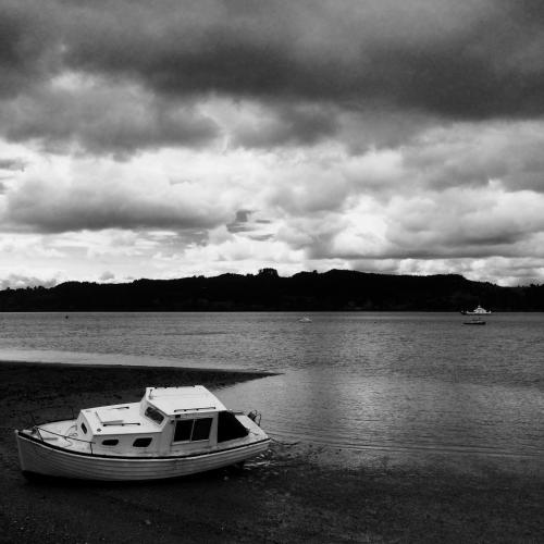 a boat sitting on the shore of a body of water at Marriners Luxury Guesthouse in Rawene