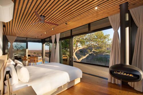 a bedroom with a fireplace in front of a large window at 57 Waterberg in Welgevonden Game Reserve