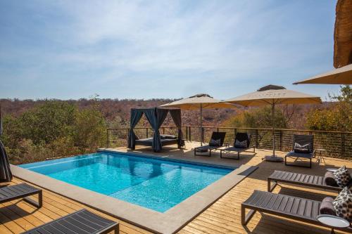 a swimming pool on a deck with chairs and umbrellas at 57 Waterberg in Welgevonden Game Reserve