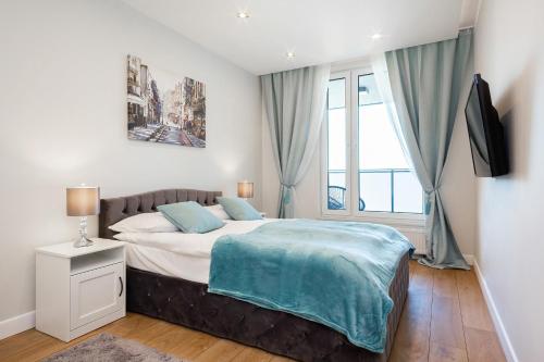 een slaapkamer met een bed en een raam bij Apartments Aura Sky by Renters in Warschau