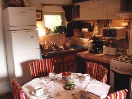 a kitchen with a table with chairs and a white refrigerator at Gîte de La Galaisière in Préaux