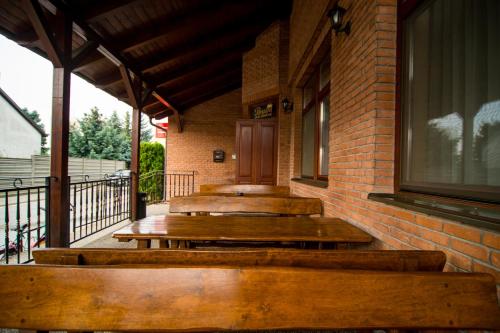 a porch with wooden benches on a brick building at Penzion Pod zámkom-Boleráz in Boleráz