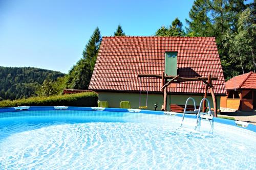 uma piscina em frente a uma casa com telhado vermelho em Domki Beskid em Rzyki