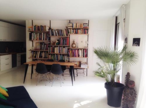 a living room with a table and a book shelf with books at Havre de paix en plein Paris in Paris