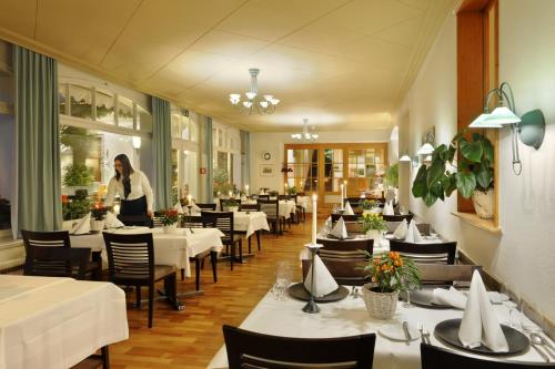 a woman standing in a restaurant with tables and chairs at Hotel Beausite Budget in Interlaken