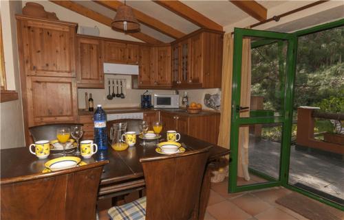 a kitchen with wooden cabinets and a table with food on it at Casa Rural en medio del bosque, El Lance in Firgas