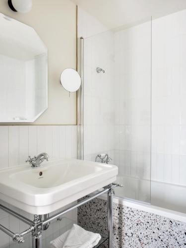 La salle de bains blanche est pourvue d'un lavabo et d'une baignoire. dans l'établissement Hôtel Léopold - Orso Hotels, à Paris