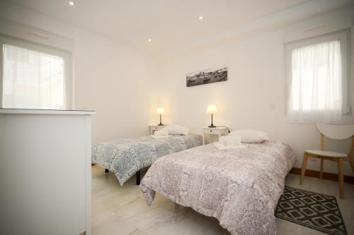 2 camas en una habitación con paredes y ventanas blancas en Apartamento Casino Praia III, en Figueira da Foz
