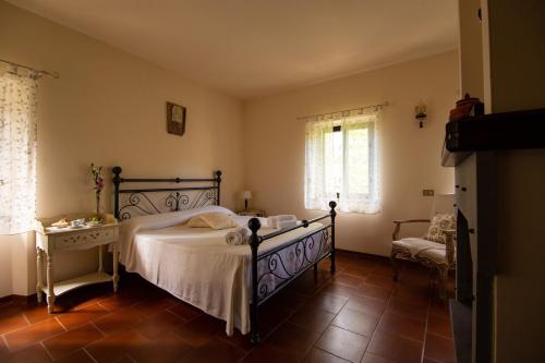 a bedroom with a bed and a chair and windows at Casale Il Trecento in Castiglion Fiorentino
