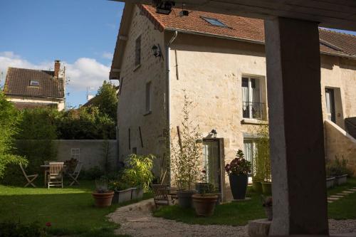 une maison dotée d'une cour avec des plantes en pot devant elle dans l'établissement Gites les Tournesols, à Auvers-sur-Oise