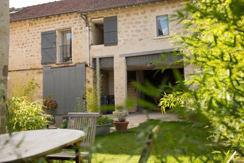 une maison en briques avec une table dans la cour dans l'établissement Gites les Tournesols, à Auvers-sur-Oise