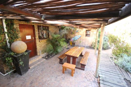 a patio with two benches and a table at Saltycrax Backpackers and Surf Hostel in Bloubergstrand