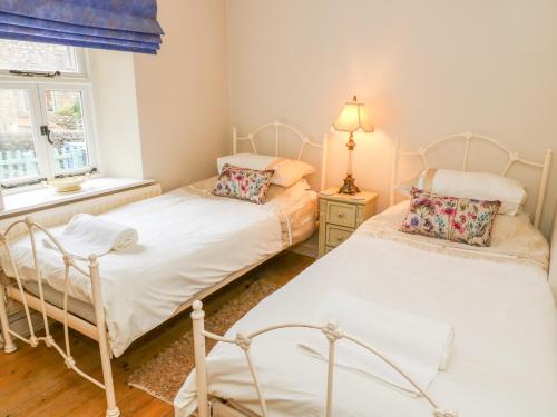two twin beds in a room with a window at Sandy Cottage in Linton