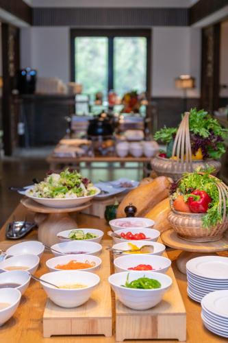 ein Buffet mit Schalen und Teller mit Speisen auf dem Tisch in der Unterkunft Pusen Lanting Shaoxing in Shaoxing