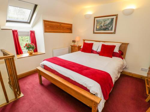 a bedroom with a large bed with red pillows at Dafarn Newydd in Dinas Mawddwy