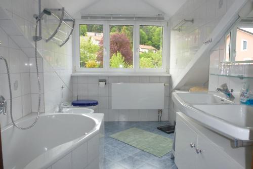 ein Badezimmer mit zwei Waschbecken, einer Badewanne und einem Fenster in der Unterkunft Ferienwohnungen Anneliese&Fritz Wagerer in Rimbach