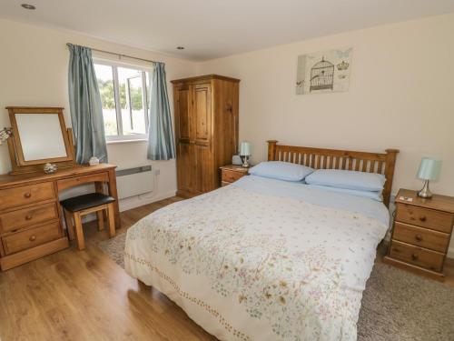 a bedroom with a bed and a desk and a mirror at Lawn Lodge in Ashleworth