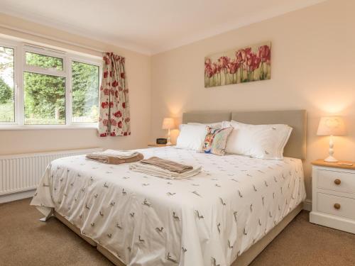 a bedroom with a large white bed and two windows at Pipistrelle Lodge in Plymtree