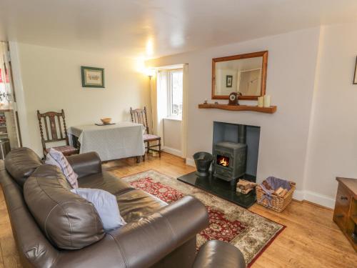 uma sala de estar com um sofá de couro e uma lareira em Kirk Cottage em Hownam