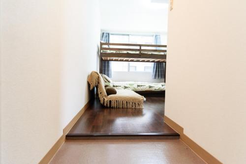 a hallway with a chair in a room with a bunk bed at Luxes Hiroshima2030 ラクセス ヒロシマ2030 in Hiroshima