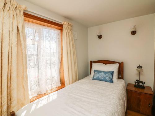 a bedroom with a bed with a blue pillow and a window at Seascape in Fethard on Sea