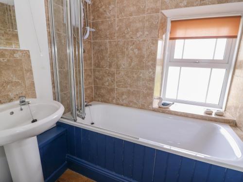a bathroom with a white tub and a sink at Cozy Cwtch Cottage in Llangynllo