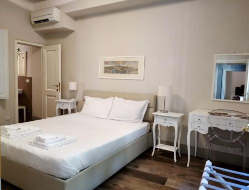 ein Schlafzimmer mit einem weißen Bett mit 2 Tischen und einem Spiegel in der Unterkunft Lanfranchi deluxe apartament in Pisa