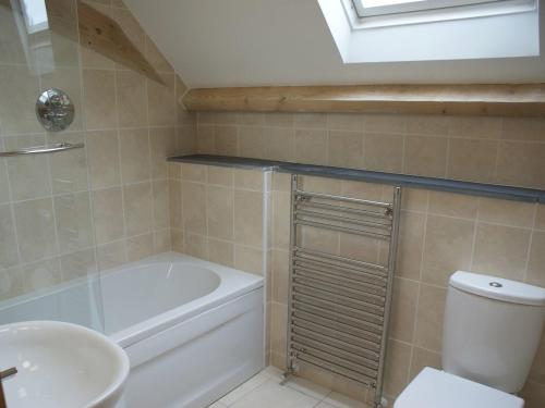 a bathroom with a tub and a toilet and a sink at Swallows Reach in Halwell