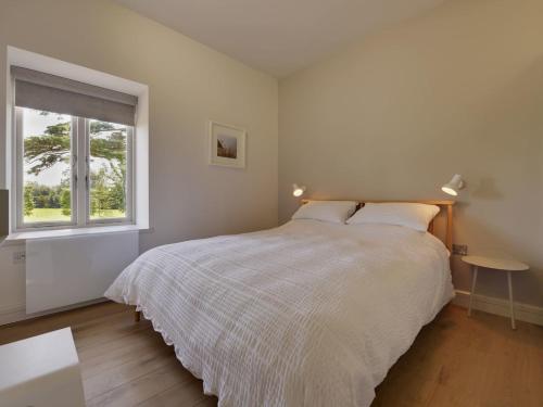 a white bedroom with a bed and a window at Gardeners Cottage in Talaton