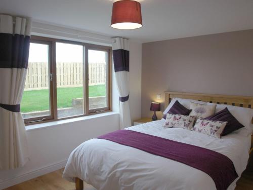 a bedroom with a bed and a large window at The Hayloft in Breage