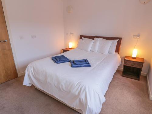 een slaapkamer met een wit bed en 2 handdoeken bij The Moorings in Isle of Whithorn