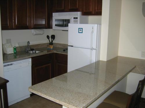 a kitchen with a white refrigerator and wooden cabinets at Staybridge Suites Indianapolis-Airport, an IHG Hotel in Plainfield