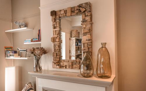 a mirror sitting on top of a fireplace with two vases at Antrim Villa Guesthouse in Cape Town