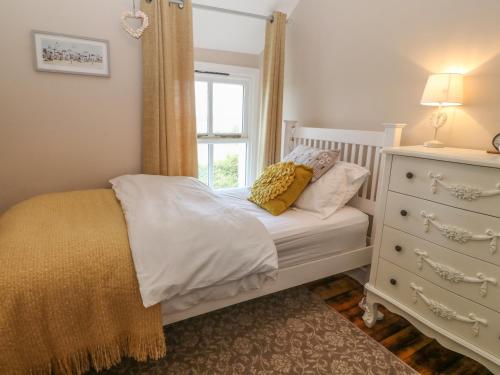 a bedroom with a bed with a window and a dresser at Glasfryn in Holyhead