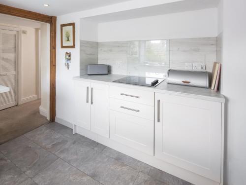 a kitchen with white cabinets and a sink at Ellwood House in Caldbeck