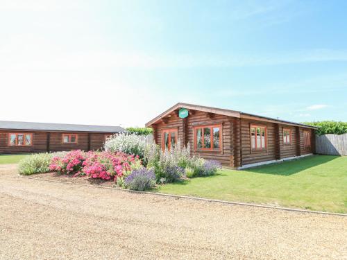a wooden house with flowers in front of it at Beech Lodge in Oakham