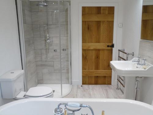 a bathroom with a shower and a tub and a toilet at Rock View Cottage in Gunnislake