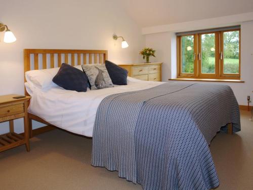 sypialnia z dużym białym łóżkiem z niebieskimi poduszkami w obiekcie The Old Log Shed w mieście Payhembury
