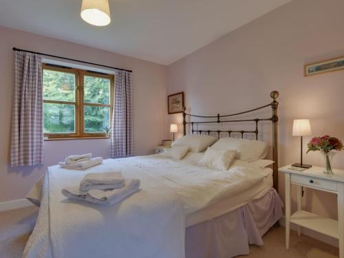 1 dormitorio con 1 cama grande y 2 toallas. en 2 Shippen Cottages en Cotleigh