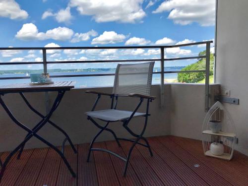 einen Stuhl und einen Schreibtisch auf einem Balkon mit Meerblick in der Unterkunft Appartement FördeMeer in Glücksburg