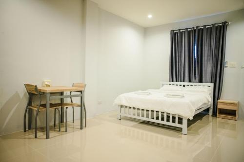 - une chambre blanche avec un lit et une table dans l'établissement Lullaby Residence, à Maha Sarakham