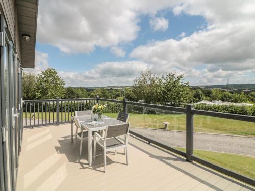 a table and chairs on the balcony of a house at Ash Lodge in Newton Abbot