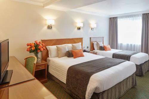 een hotelkamer met 2 bedden en een televisie bij Lancaster Gate Hotel in Londen